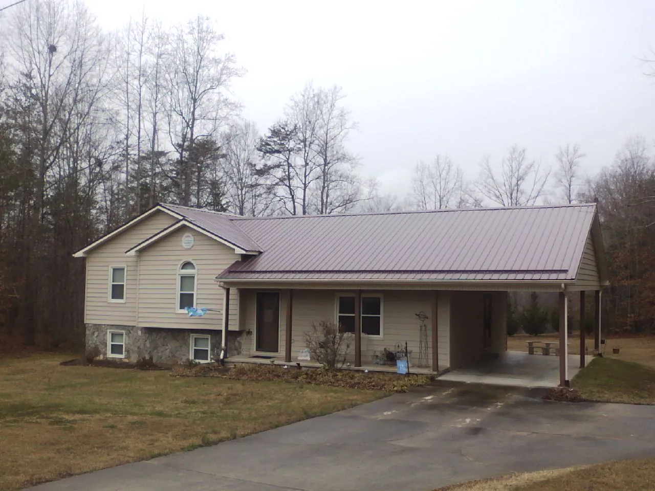 Burgundy metal roof on a tan split level home with an attached carport in Polk City