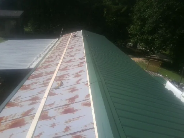 Old rusted panels beside newly installed green metal roofing — Wind Damage Roof Repair by Roofing Brothers in Polk City