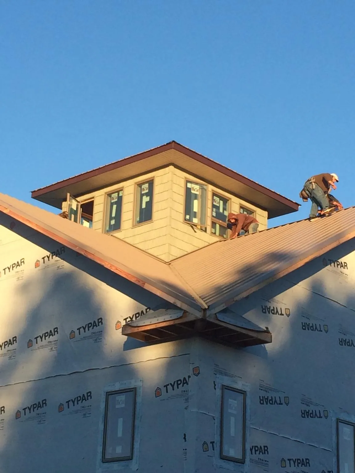 Roofers working around a rooftop cupola on a new metal roof at sunset — Roof Waterproofing in Polk City by Roofing Brothers